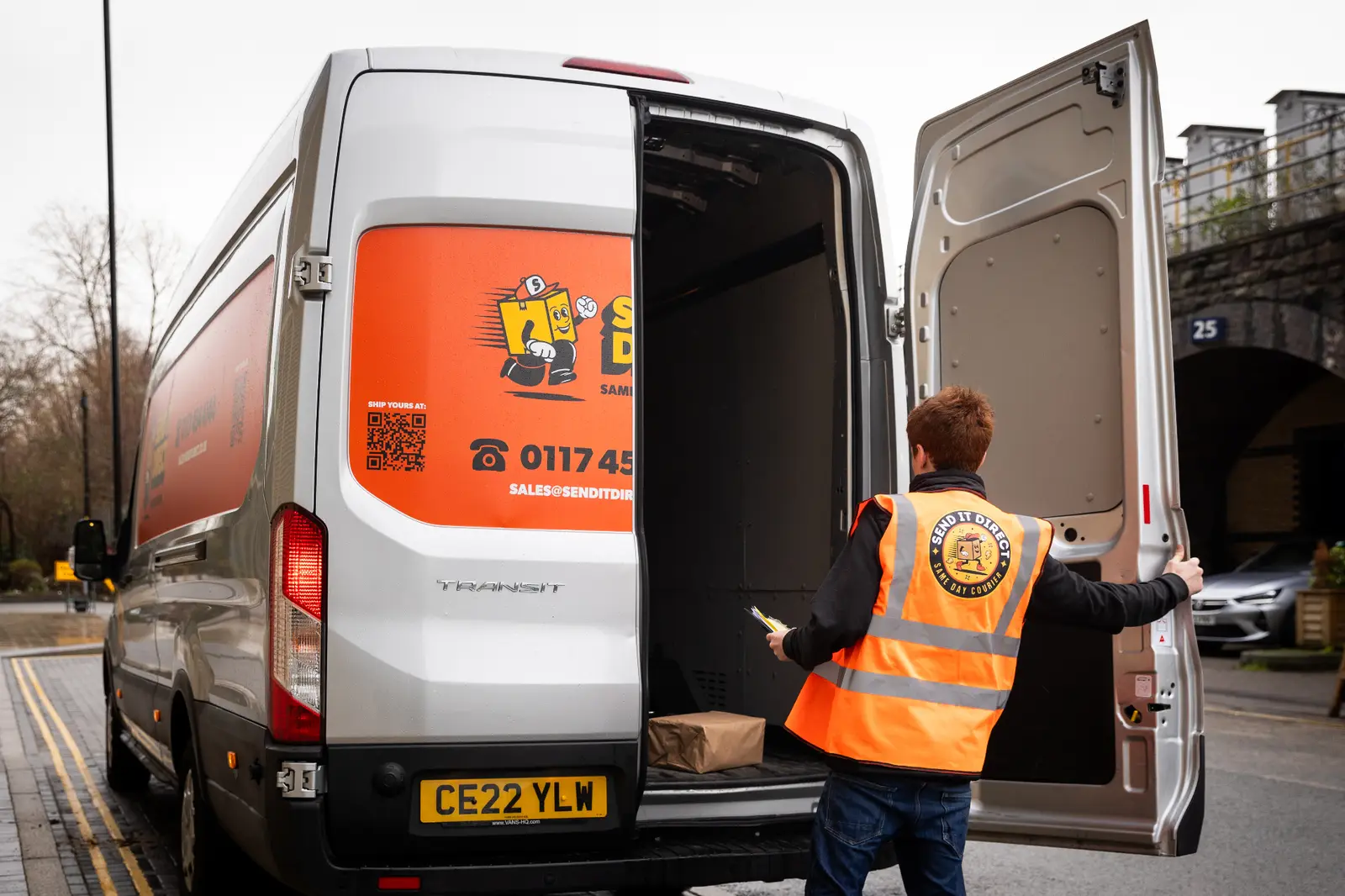 Same-day courier driver loading an urgent parcel into a delivery van in the UK