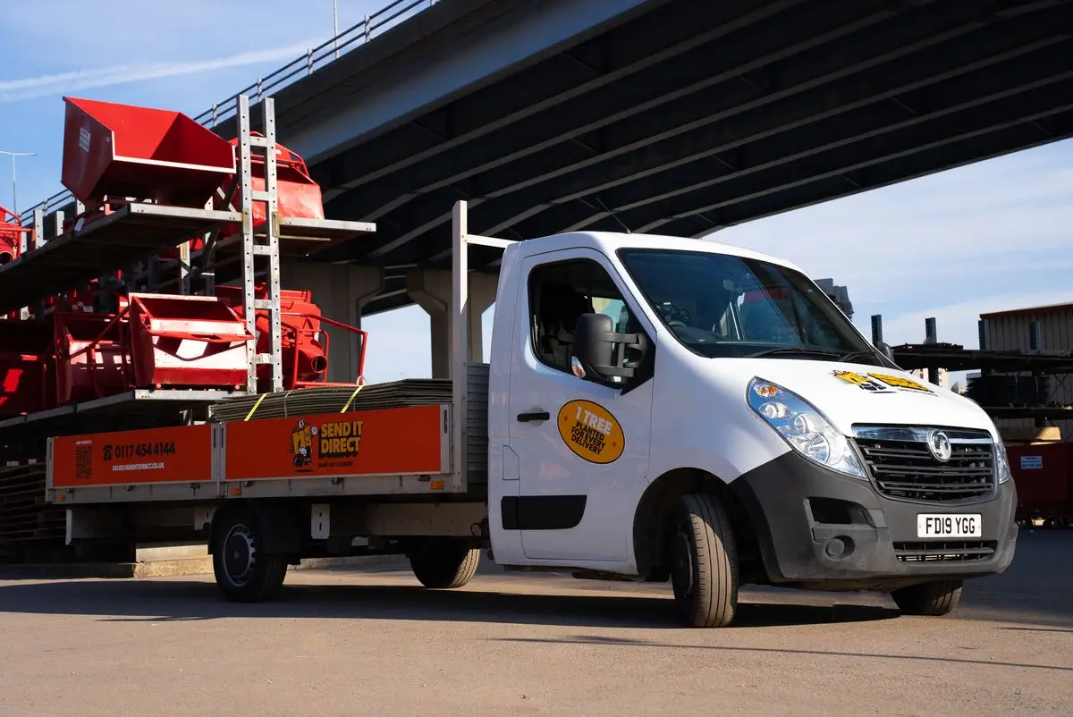 Flatbed lorry loaded with plant machinery on a UK road