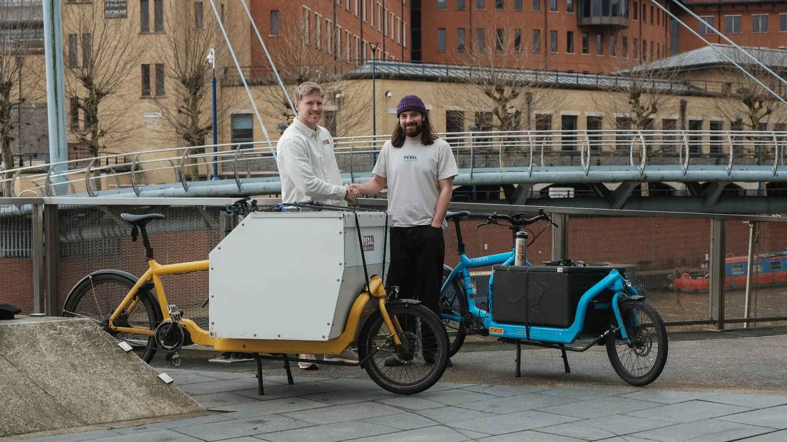 Send It Direct and Pedal Collective founders shaking hands with cargo bikes in Bristol harbour